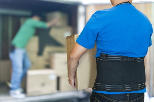 man wearing a back brace while lifting a heavy box