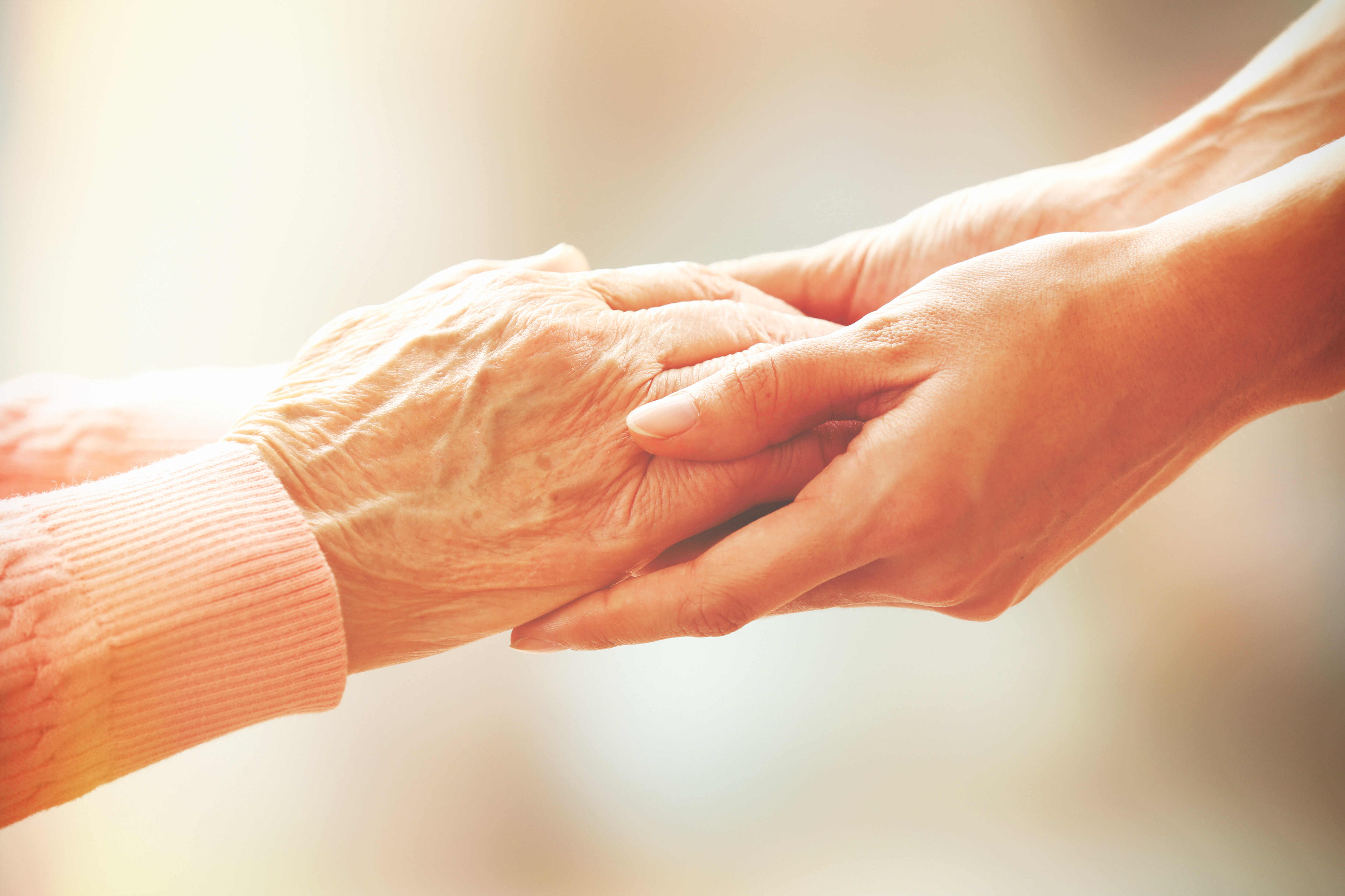 younger looking hands holding the hands of an elder