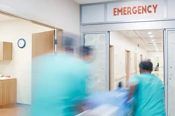 Healthcare professionals rush through an ER entrance labeled Emergency, illustrating urgent medical,.