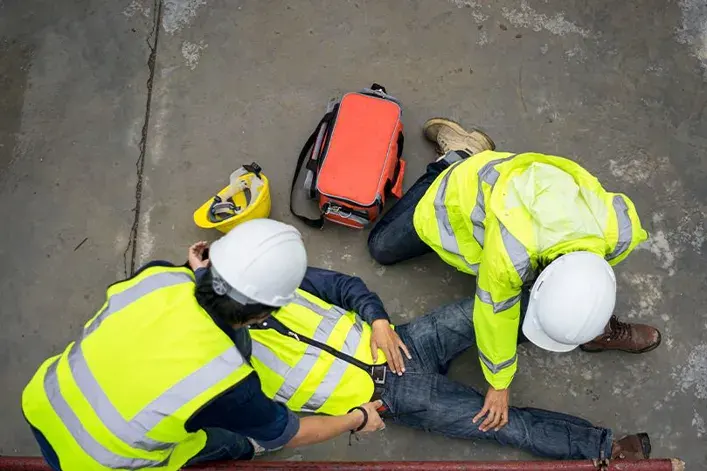 Attorney assisting injured worker at a construction site with high-visibility vests and safety gear,.